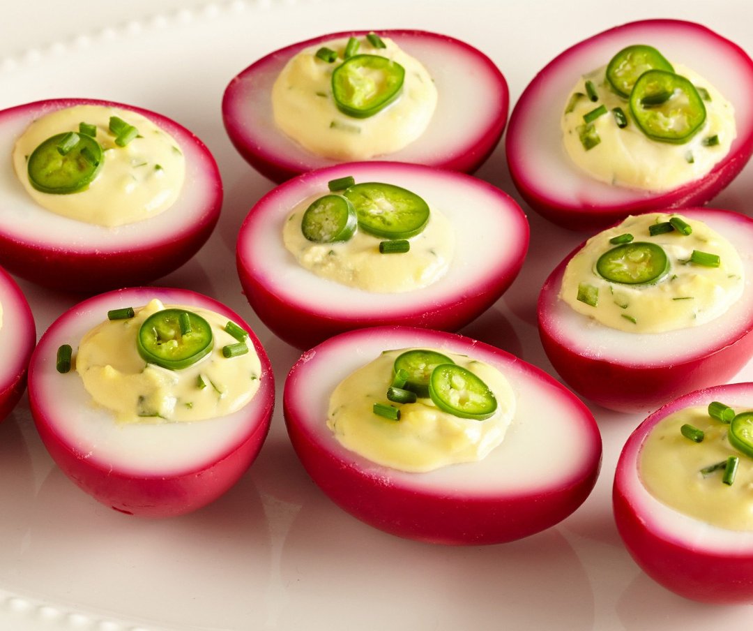 Фаршированные яйца с подкрашенными свекольным цветом белками на блюде